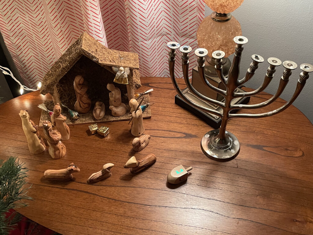 a Nativity scene with mostly wooden figures; a menorah without candles; a wooden dreidel