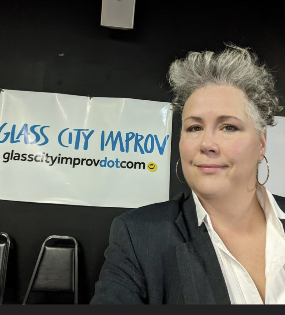 Diana DePasquale standing in front of the “Glass City Improv” banner in the Valentine Theater’s Studio A.

glasscityimprov.com