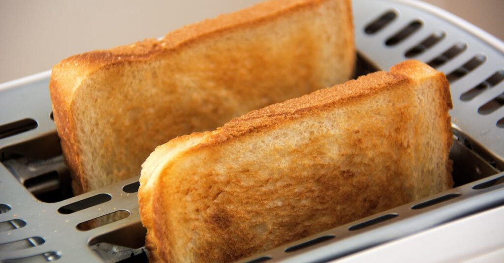 A public-domain photo of two slices of white, toasted bread emerging from a toaster.