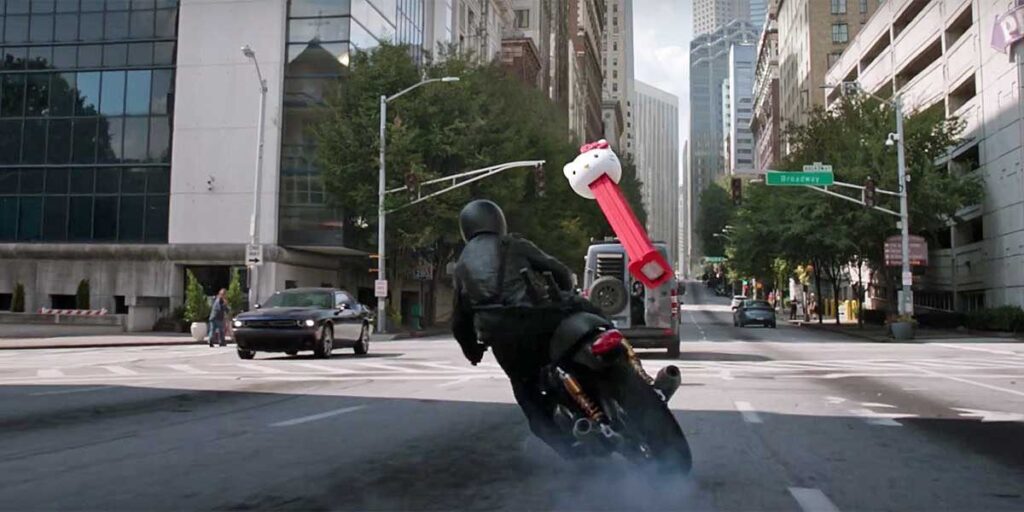 A screenshot from ANT-MAN (2015). A motorcyclist is trying to spin away from the oncoming threat of a giant Pez dispenser with a Hello Kitty head.