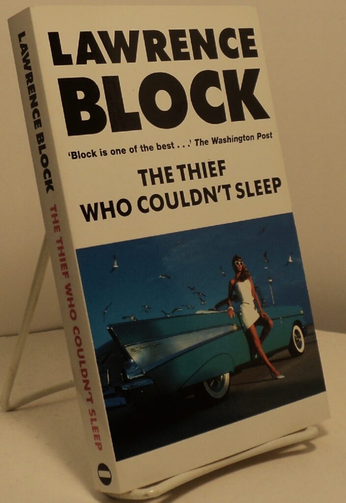 Photo of a paperback copy of Block's THE THIEF WHO COULDN'T SLEEP. The cover illustration shows a blonde woman leaning against the side of a wide-finned American car from the 1950s.